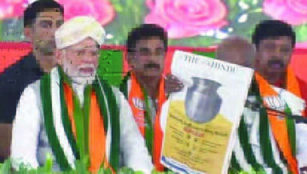 கருநாடகாவில் பா.ஜ.க. மேடையில் மோடி முன்னிலையில் காங். விளம்பரத்தை காட்டிய தேவேகவுடா இந்தியா